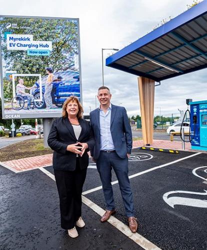 Cabinet Secretary for Transport, Fiona Hyslop and Lead Director, EV at SSE Energy Solutions, Simon Cowling pose in front of an EV charging bay at the Myrekirk Roundabout in Dundee.